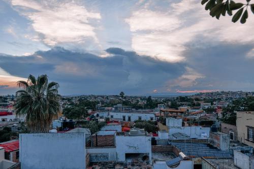 a city with a palm tree and a cloudy sky at Casa Maricela B&B in San Miguel de Allende