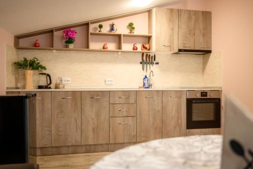 a kitchen with wooden cabinets and flowers on the wall at Апартаменти ЗДРАВЕ in Sapareva Banya