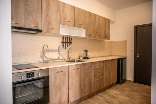 a kitchen with wooden cabinets and a sink at Апартаменти ЗДРАВЕ in Sapareva Banya
