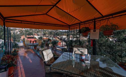 uma mesa e cadeiras numa varanda com um guarda-sol laranja em Casa Maricela B&B em San Miguel de Allende