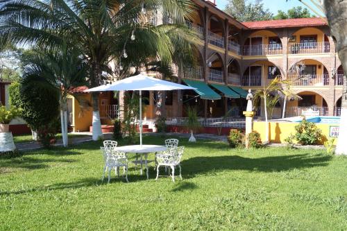 a table with chairs and an umbrella in front of a building at Hotel HF Hacienda San Francisco in Puente Nacional