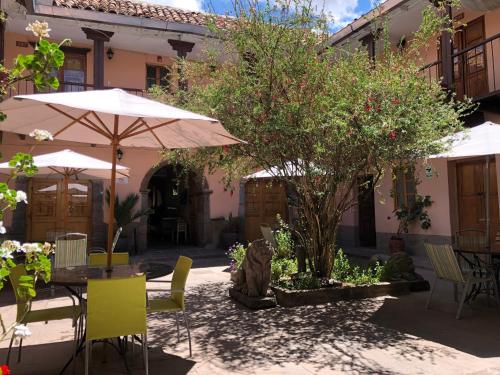 an outdoor patio with tables and chairs and umbrellas at Hostal Qorichaska in Cusco