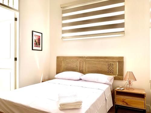 a bedroom with a white bed with a wooden headboard at Casa Rambla Serra Cali in Cali