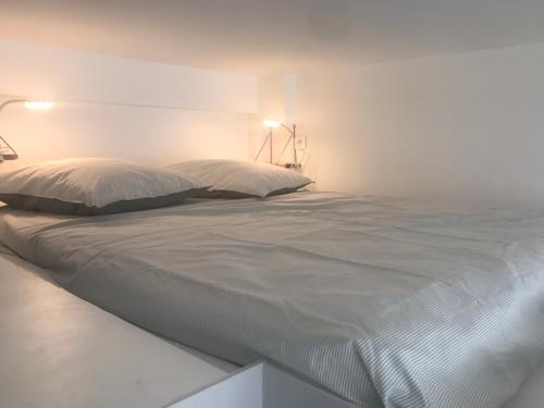 - un grand lit blanc dans une chambre blanche avec deux oreillers dans l'établissement St Marc appartement 4 Personnes au Centre de Paris, à Paris