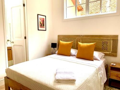 um quarto com uma cama grande e almofadas amarelas em Casa Rambla Serra Cali em Cali