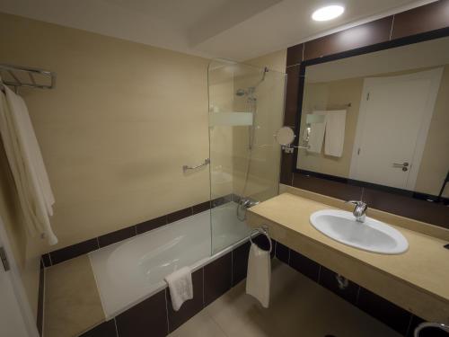 
a bathroom with a sink, toilet and mirror at Hotel Lanzarote Village in Puerto del Carmen
