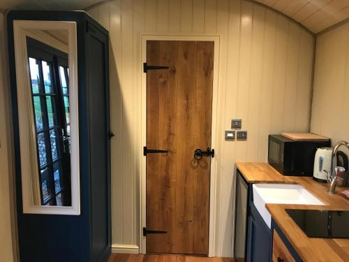 a kitchen with a wooden door and a sink at Highkettle Hut in Chichester