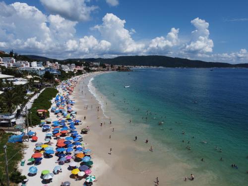 uma praia com guarda-sóis e pessoas na água em RESIDENCIAL MAR BLUE em Bombinhas