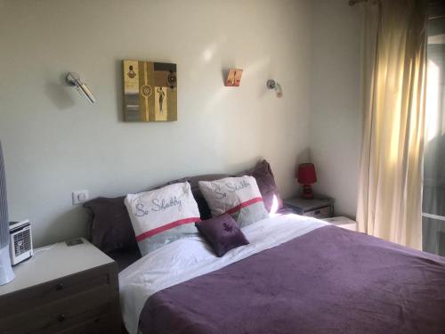 um quarto com uma cama com lençóis e almofadas roxos em Warblers View em Biot