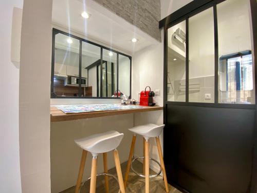 ein Badezimmer mit zwei Hockern an einer Theke mit einem Spiegel in der Unterkunft Studios Sauzède - Carcassonne centre-ville in Carcassonne