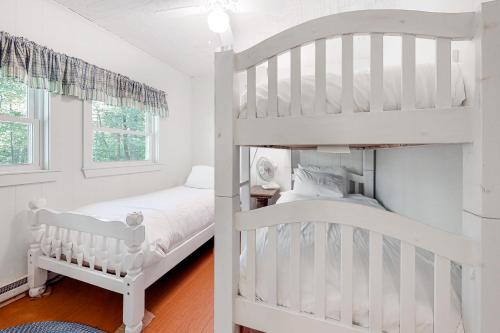 a white bedroom with a bunk bed and a crib at 20 Island Drive in Madison