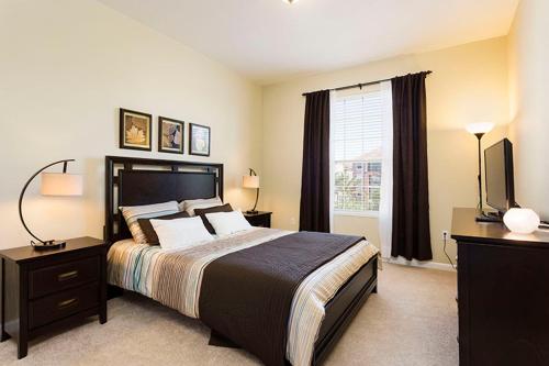 a bedroom with a large bed and a television at 3Br 2Bath Condo Balcony 5min Conv Center 1410ft in Orlando