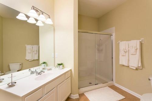 a bathroom with a shower and a sink and a mirror at 3Br 2Bath Condo Balcony 5min Conv Center 1410ft in Orlando