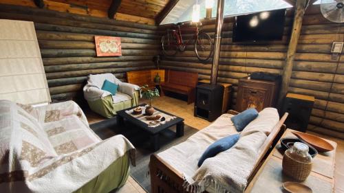 una sala de estar con 2 sillas y TV en una cabaña de madera en Cabañas Rústicas, en Estación Colina