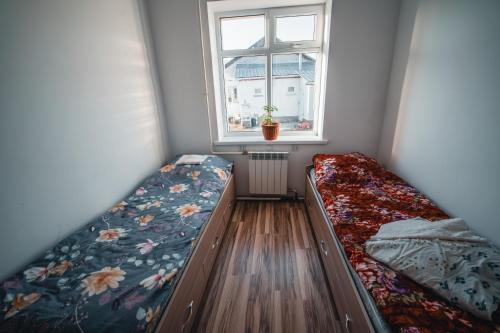 Cette petite chambre comprend 2 lits et une fenêtre. dans l'établissement Sarysoul Mountainlodge / Pamirextreme, à Sary-Tash