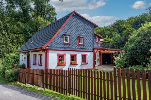 a small red and white house with a fence at Vlčihorská chaloupka in Krásná Lípa