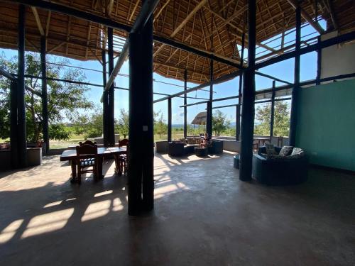 a large pavilion with a table and chairs and windows at Enshama Game Lodge and Campsite in Katunguru