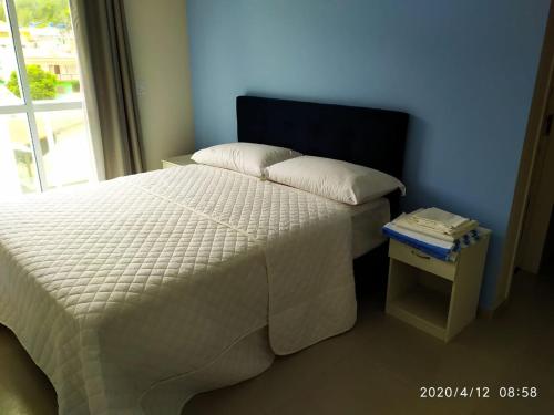 um quarto com uma cama e uma mesa de cabeceira ao lado de uma janela em Cobertura Fort do Pontal em Arraial do Cabo