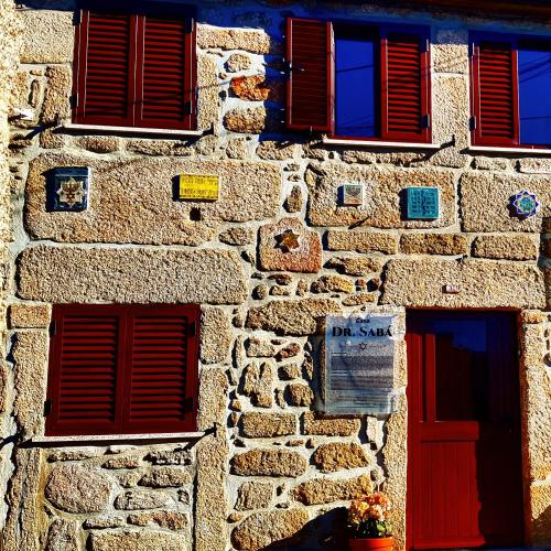a stone building with red windows and a sign on it at Casa Dr. Saba in Belmonte