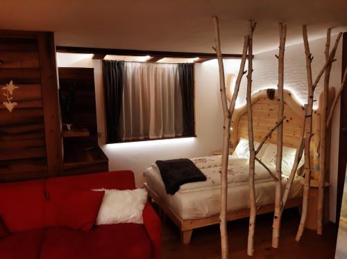 a bedroom with a bed and a red couch at Appartamento Cirmolo in Peio
