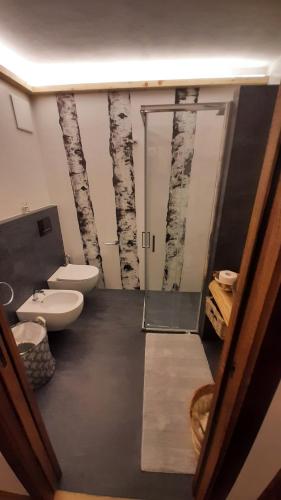a bathroom with a toilet and a shower with trees on the wall at Appartamento Cirmolo in Peio