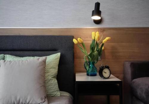 a vase with yellow flowers on a table with a clock at Studio Four Seasons with parking place in Gdańsk