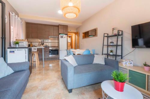 sala de estar con 2 sofás azules y cocina en Apartamento Turístico Javalambre, en Camarena de la Sierra