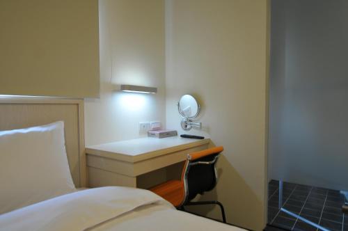 a room with a bed and a desk with a mirror at Century Hotel in Kaohsiung