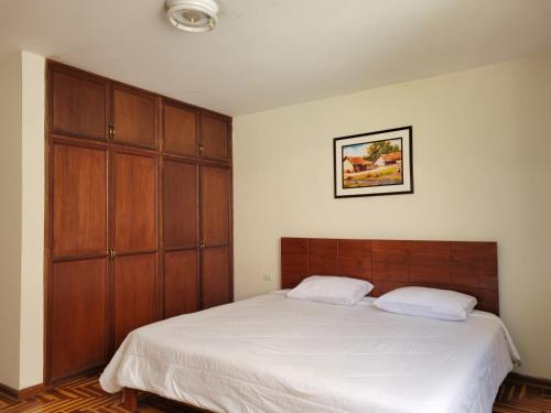 um quarto com uma cama grande e armários de madeira em Departamento Los Sauces em Cajamarca