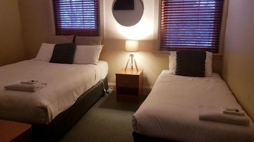 two beds in a small room with two windows at Highlands Hotel in Mittagong