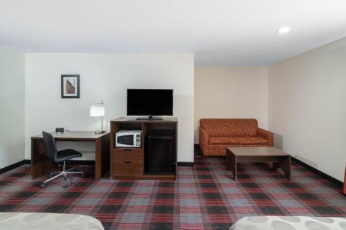 a hotel room with a couch chair and a television at Ramada by Wyndham Maggie Valley in Maggie Valley