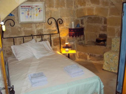 1 dormitorio con cama y pared de piedra en La Gozitaine en Kerċem