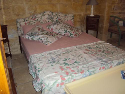 a bedroom with a large bed with a flowery comforter at La Gozitaine in Kerċem