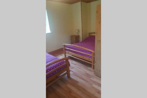 two beds in a room with purple sheets at Cottage ideal for Family's & private lake access in Leitrim
