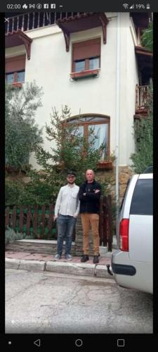 two men are standing in front of a house at oniron in Sidhirókastron
