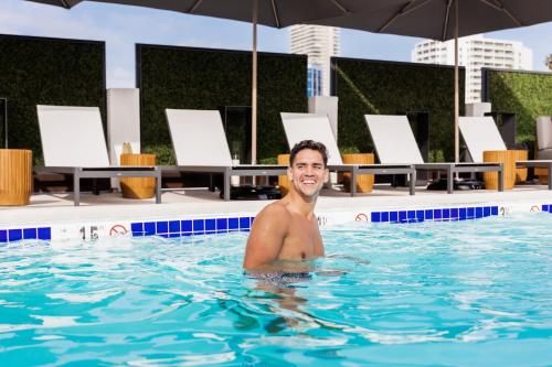 un hombre en la piscina de un hotel en Montrose at Beverly Hills, en Los Ángeles