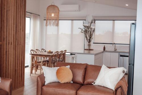 a living room with a brown couch and a kitchen at Ocean Oasis Port Campbell in Port Campbell