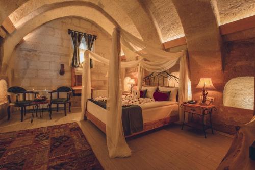 a bedroom with a canopy bed and a table at Rose Valley Hotel in Goreme