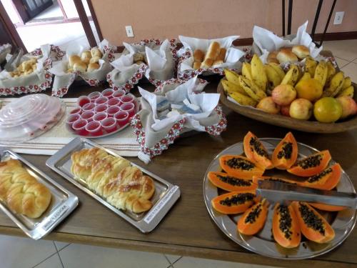 a table topped with plates of food and fruit at Pousada Finlândia in Penedo