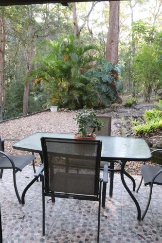 a patio with a table and chairs and a potted plant at GREEN TREES CHALET Australia Zoo close by in Landsborough