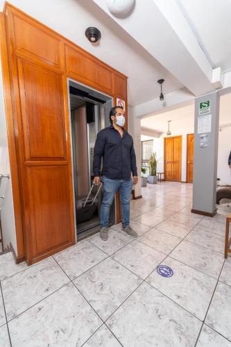 a man with a face mask cleaning a door at Samana Hotel in Arequipa