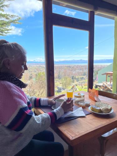 a woman sitting at a table in front of a window at Bla Lodge in El Calafate