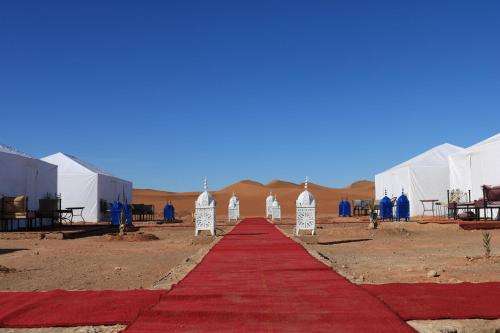 Una alfombra roja frente a tiendas de campaña en el desierto. en Luxury Berber Camp, en El Gouera