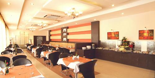 un comedor con mesas y sillas en un restaurante en Regency Tuticorin by GRT Hotels, en Thoothukudi