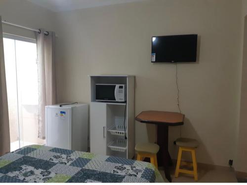 um quarto com uma cama, uma televisão e uma mesa em Apês do Peró - Centro - suíte 03 em Cabo Frio