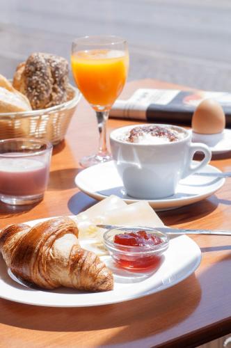 a table with a breakfast of coffee and croissants and orange juice at Egon Hotel Hamburg City in Hamburg
