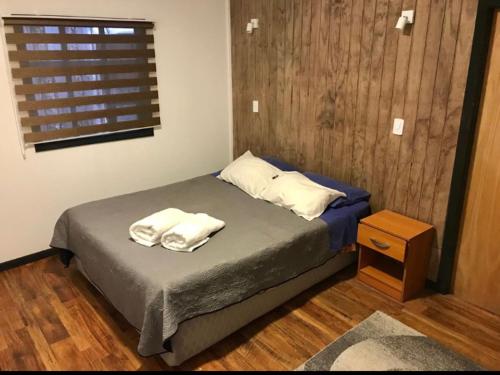 a bedroom with a bed with two towels on it at El Sendero in Puerto Natales
