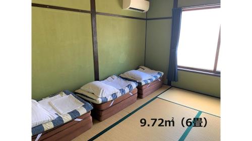 a room with three beds in it with a window at Matsue Guesthouse in Matsue