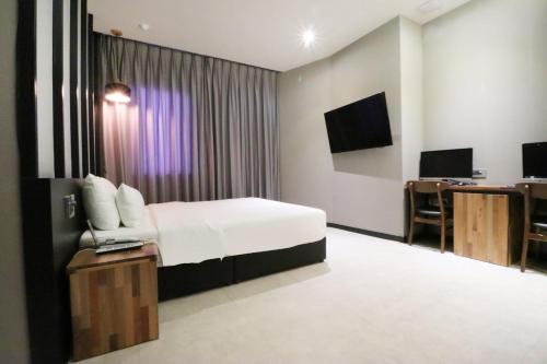 a bedroom with a bed and a desk and a television at Hotel Marcher in Busan