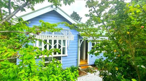 a blue house with a white window and trees at Plum Blossom Cottage in Katoomba